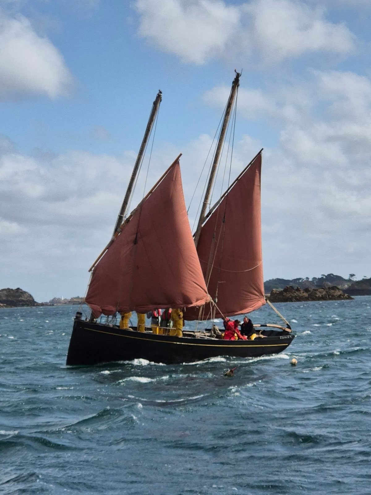 A Breton gaffer under red sails off the pink granite A Breton gaffer under red sails off the pink granite